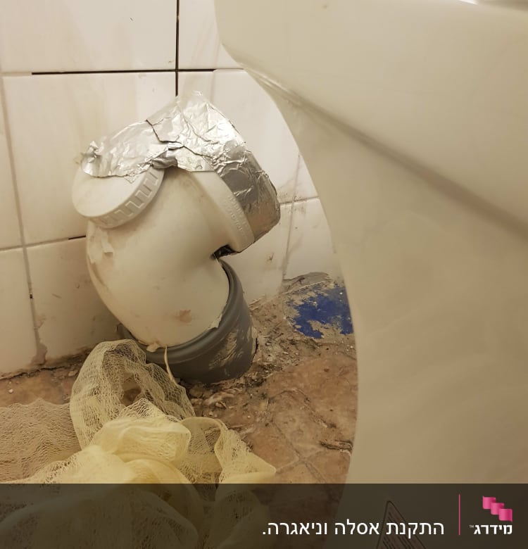 צינור ביוב עם תיקון בנייר כסף ליד אסלה